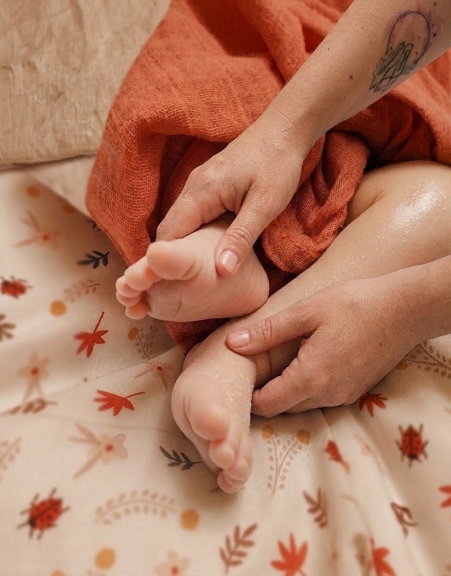 Mains adultes massant les petits pieds d’un bébé